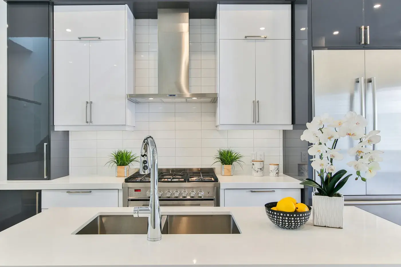 Modern kitchen with gloss white and grey cabinets, polished quartz island and stainless range hood after a Deep Cleaning service